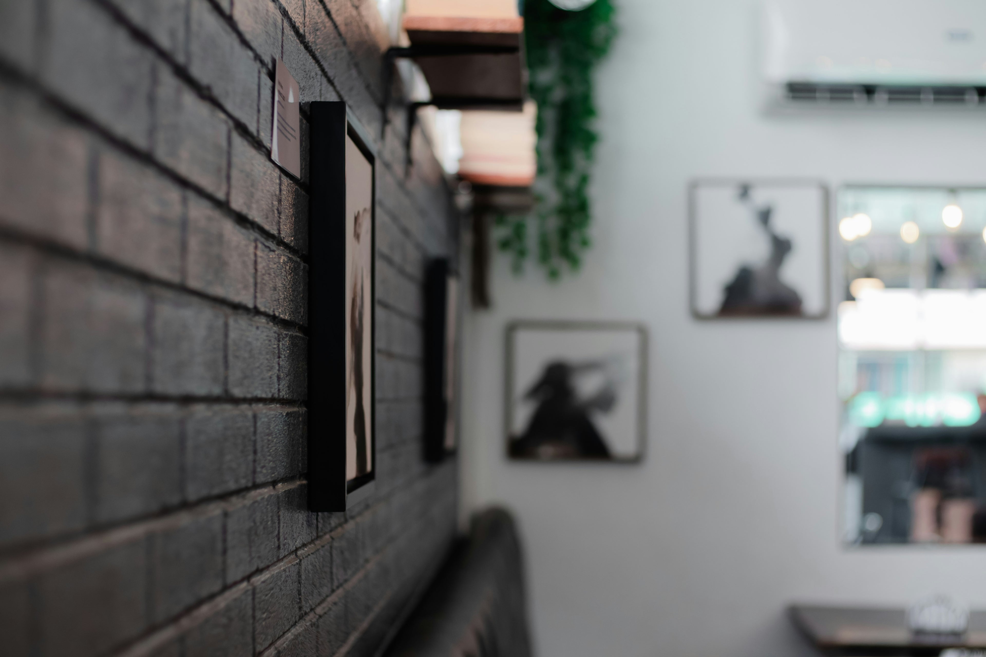 Restaurant interior with brick wall, framed pictures, and a window view.